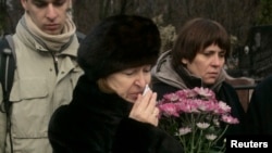 Nataliya Magnitskaya (L), mother of Sergei Magnitsky, grieves over her son 's body during his funeral at a cemetery in Moscow, November 20, 2009.