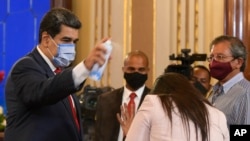Venezuelan President Nicolás Maduro jokes with a journalist, spraying her with a disinfectant, at the end of a press conference in Caracas, Venezuela on December 8, 2020. (AP Photo/Matías Delacroix)