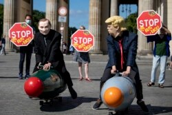 GERMANY -- Two activists dressed up as U.S. President Trump and Russian President Putin ride two atomic bomb models during a protest for a world without nuclear weapons in front of the Brandenburg Gate in Berlin, July 30, 2020