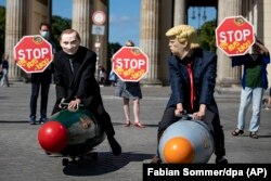 GERMANY -- Two activists dressed up as U.S. President Trump and Russian President Putin ride two atomic bomb models during a protest for a world without nuclear weapons in front of the Brandenburg Gate in Berlin, July 30, 2020