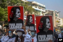 Anti-coup protesters display pictures of deposed Myanmar leader Aung San Suu Kyi in Yangon on March 2, 2021. (Associated Press)