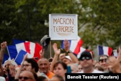 A protester holds a placard that reads "Macron terrorist" during a demonstration called by the French nationalist party "Les Patriotes" (The Patriots) against France's restrictions to fight the coronavirus disease (COVID-19) outbreak, in Paris, France, June 24, 2021.