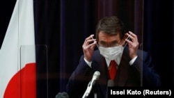 FILE PHOTO: Japan's vaccination program chief Taro Kono adjusts his protective face mask during a news conference in Tokyo, Japan February 16, 2021.