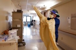 Registered Nurse Monica Quintana dons protective gear before entering a room at the William Beaumont hospital on April 21, 2021, in Royal Oak.
