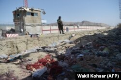 A Taliban fighter stands guard at the site of the August 26, 2021, suicide bomb attack, which killed scores of people, including 13 US troops, at Kabul airport. (Wakil Kohsar/AFP)