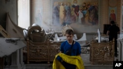 A boy helps salvage items at the Odesa Transfiguration Cathedral after it was heavily damaged in Russian missile attacks in Odesa, onJuly 23, 2023. (Jae C. Hong/AP)