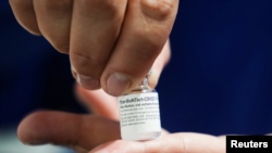 A healthcare worker shows a vial of the Pfizer/BioNTech vaccine against the coronavirus disease (COVID-19) at a parking lot of an exhibition center turned into a vaccination center, in Bogota, Colombia June 8, 2021. REUTERS/Nathalia Angarita