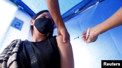 A woman receives a dose of the Pfizer/BioNTech vaccine against the coronavirus disease (COVID-19) at a sport stadium in Vina del Mar, Chile, on April 22, 2021. 