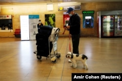 A passenger checks his phone as he stands with his dog after arriving on a flight to Israel at Ben Gurion international airport amid coronavirus disease (COVID-19) restrictions near Tel Aviv, in Lod, Israel March 8, 2021.