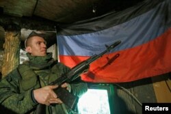 A militant of the self-proclaimed Donetsk People's Republic (DNR) holds a weapon on the line of separation from the Ukrainian armed forces south of the rebel-controlled city of Donetsk on April 2, 2021.