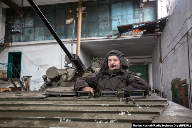 A soldier from a unit of Ukraine's airborne assault brigade sits in a light tank in a warehouse serving as a forward position at Novoluhanske, opposite Russian-backed separatists in the Donbas region, on February 22, 2022. (Marian Kushnir/RFE/RL)