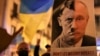 A person holds a banner with the joined faces of a portrait of Vladimir Putin and Adolf Hitler during an anti-war protest in Barcelona, Spain, February 24, 2022. REUTERS/Nacho Doce