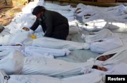 A man holds the body of a dead child among bodies of people activists say were killed by nerve gas in the Ghouta region, in the Duma neighbourhood of Damascus August 21, 2013.