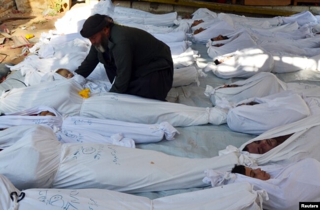 A man holds the body of a dead child among bodies of people activists say were killed by nerve gas in the Ghouta region, in the Duma neighbourhood of Damascus August 21, 2013.