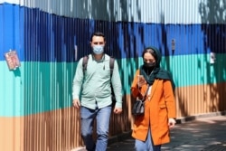 Iranians wearing protective masks walk on a sidewalk in the capital Tehran, April 12, 2021.