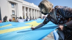 People write wishes on a large Crimean Tatar flag outside the parliament building in Kyiv on June 15, 2021.