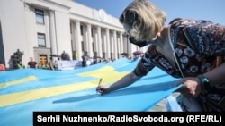 People write wishes on a large Crimean Tatar flag outside the parliament building in Kyiv on June 15, 2021.