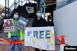 Pro-democracy supporters in December 2020 call for the release of 12 Hong Kong activists arrested as they reportedly sailed to Taiwan for political asylum and citizen journalist Zhang Zhan outside of China's Liaison Office.