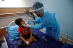 A medical team member takes a swab sample from a child who suffers from cancer to test for the coronavirus disease (COVID-19), at the Children's Hospital for Cancer Diseases in Basra, Iraq July 12, 2020.