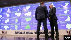 Two men stand in front of an information board at the Russia's Central Election Commission office in Moscow on September 8, 2023. (Photo by AFP)