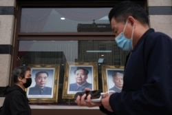 People wearing face masks walk past portraits of late Chinese Communist Party leaders (L-R) Zhou Enlai, Mao Zedong and Liu Shaoqi. This photo was taken on on May 7, 2020, in Beijing.