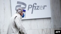 In this file photo taken on March 11, 2021, a man wearing facemask and shield walks past the Pfizer headquarters in New York one year after the pandemic was officially declared. (Photo by Kena Betancur/AFP)