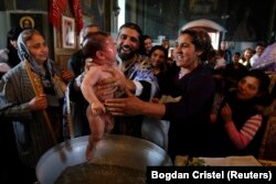 ROMANIA -- Priest Nicolae Ganga (C) baptizes a child during a mass Orthodox baptism ceremony at a church in the Bora neighborhood in Slobozia, November 29, 2012.