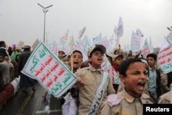 Children hold signs as supporters of the Houthis rally to denounce the U.S. labeling of the Houthis as a 'Specially Designated Global Terrorist' group, in Sanaa on January 19, 2024. (Khaled Abdullah/Reuters)