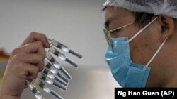 CHINA -- A worker inspects syringes of a vaccine for COVID-19 produced by Sinovac at its factory in Beijing, September 24, 2020.