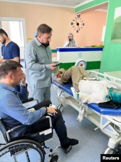 Human Rights Commissioner in the Chechen Republic, Mansur Soltaev, visits Yelena Milashina, a journalist for the now-banned independent newspaper Novaya Gazeta, and lawyer Alexander Nemov in hospital after they were attacked in Grozny, Chechnya on July 4, 2023. (Crew Against Torture/Handout via Reuters)